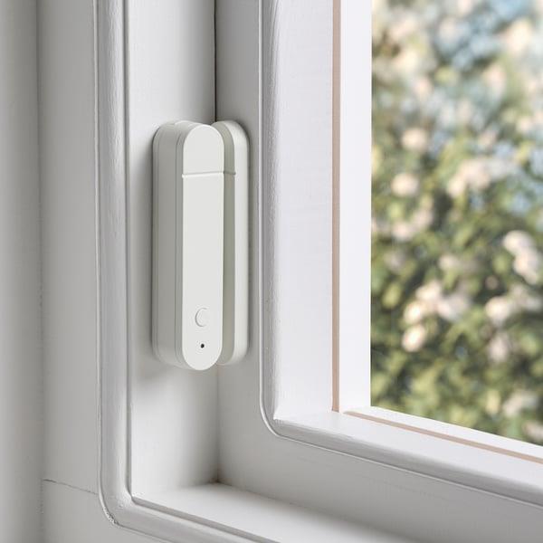 A small contact sensor installed on a window frame.